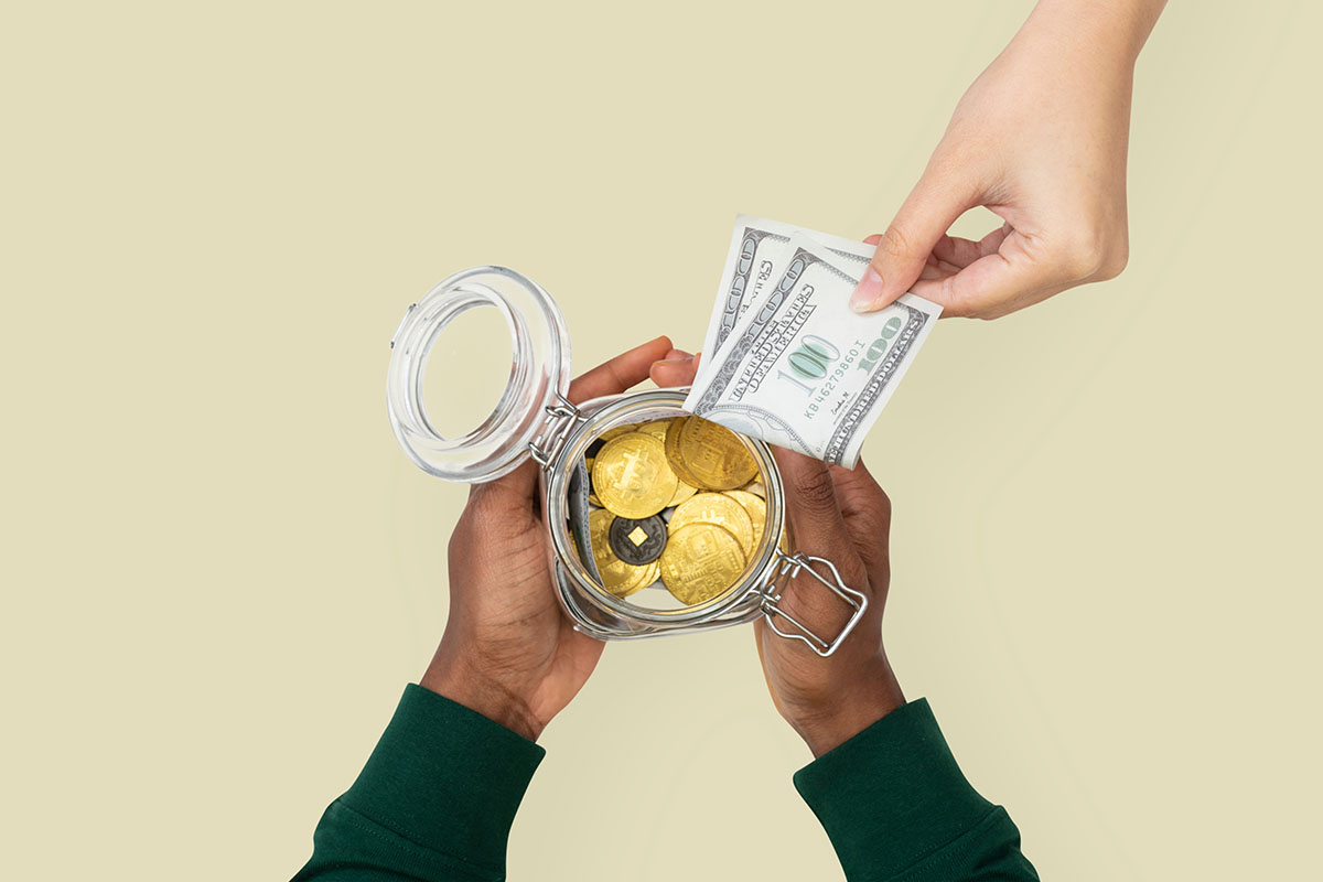 Hands placing currency into a donation jar